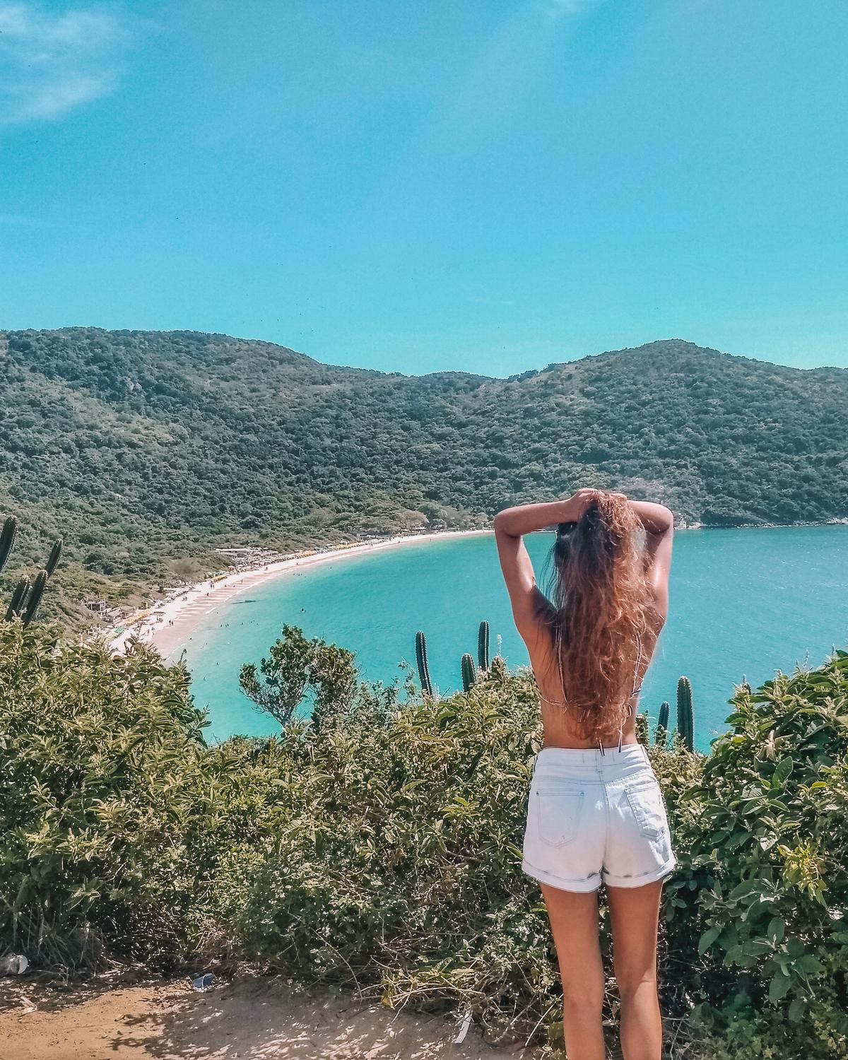 Mujer contemplando la vista de la Playa do Forno en Arraial do Cabo desde un mirador natural, ideal para los amantes de la naturaleza y fotógrafos.